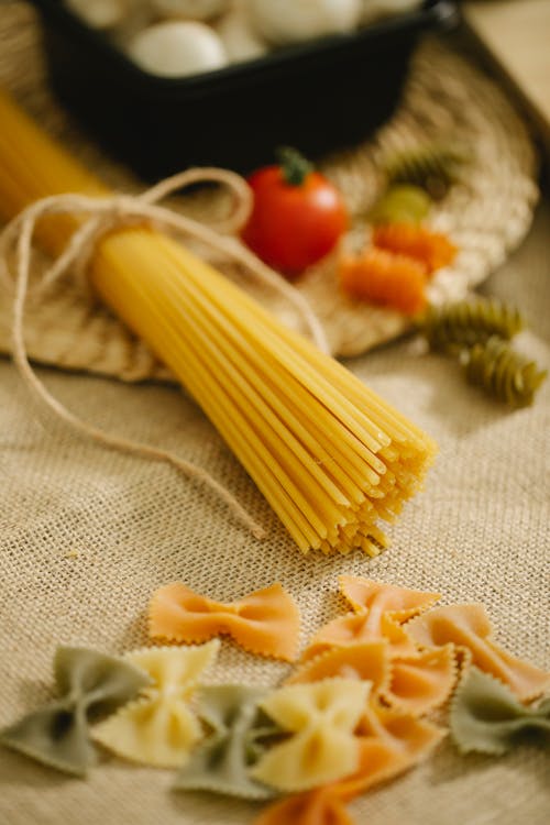 Raw spaghetti and farfalle arranged on table