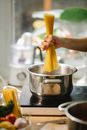 Crop faceless chef putting spaghetti into saucepan in kitchen
