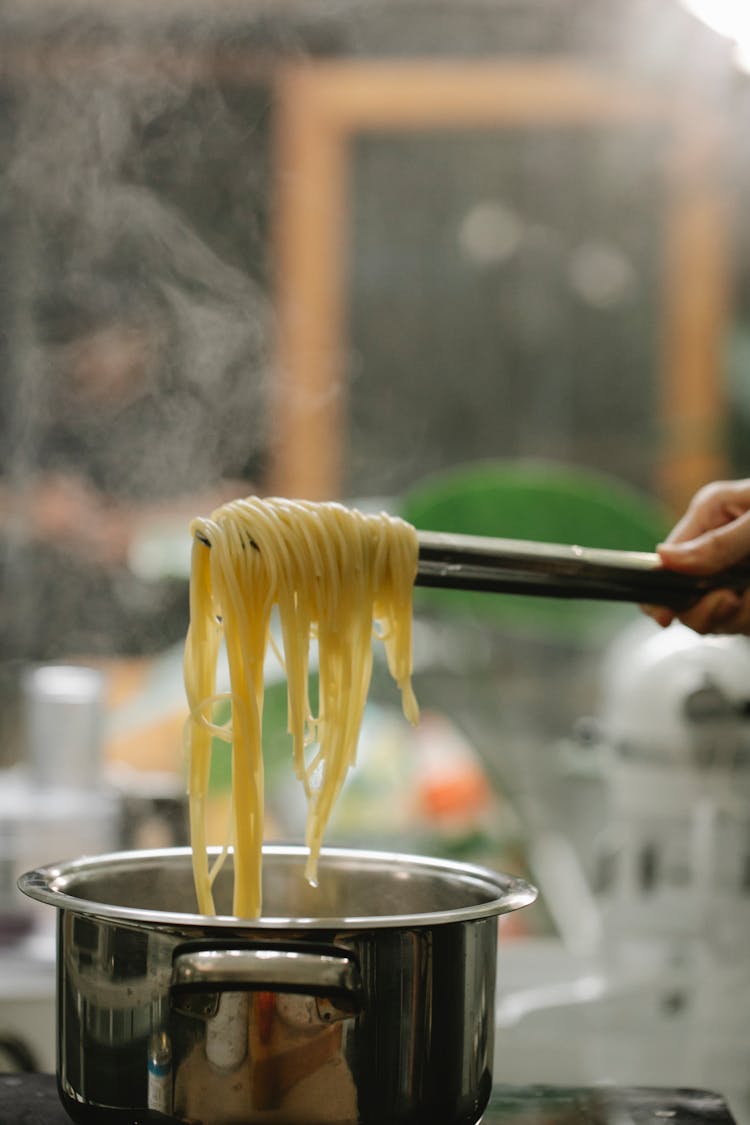 Crop Faceless Chef Picking Cooked Spaghetti With Tongs