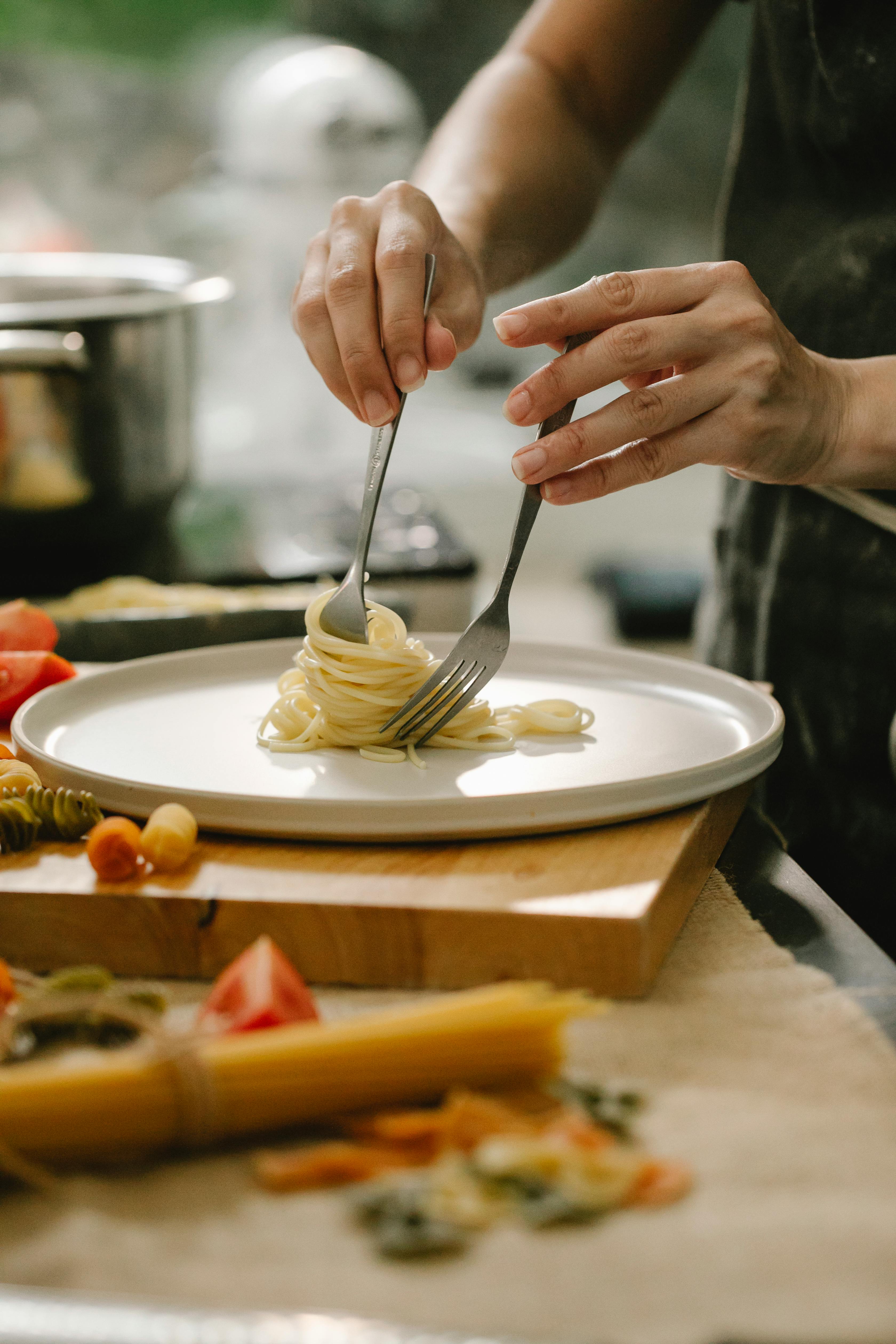 crop faceless housewife serving delicious spaghetti on plate