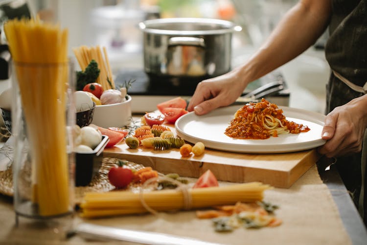 Person Cooking Pasta With Meat And Tomatoes