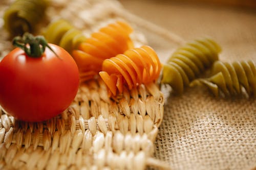 Fresh tomatoes and raw pasta on table