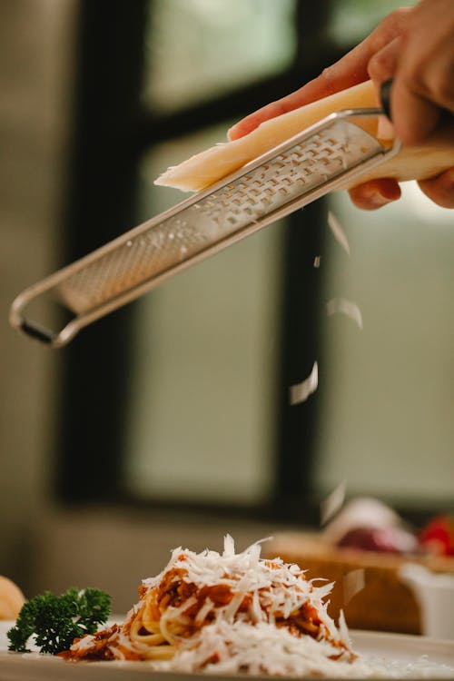 Crop faceless chef grating cheese on appetizing spaghetti