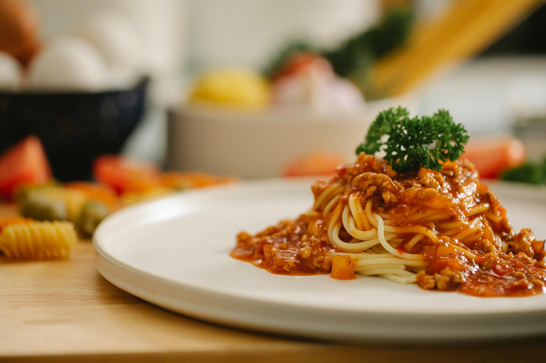 Delicious yummy spaghetti pasta with Bolognese sauce garnished with parsley and served on table in light kitchen