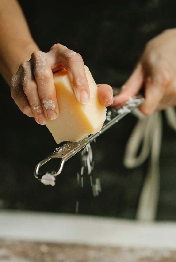 Crop Unrecognizable Chef Grating Cheese In Kitchen