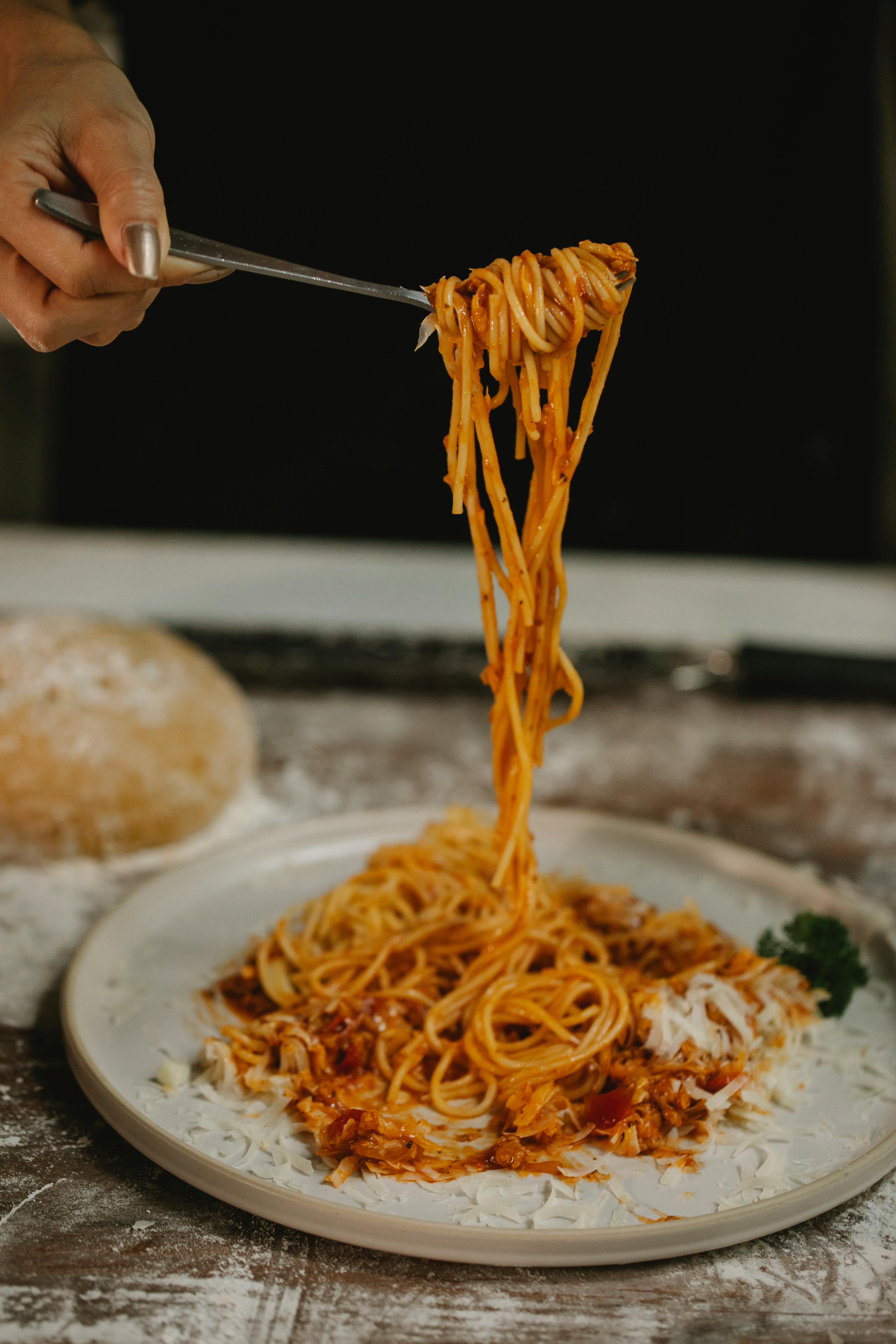 crop unrecognizable woman eating delicious spaghetti with tomato sauce