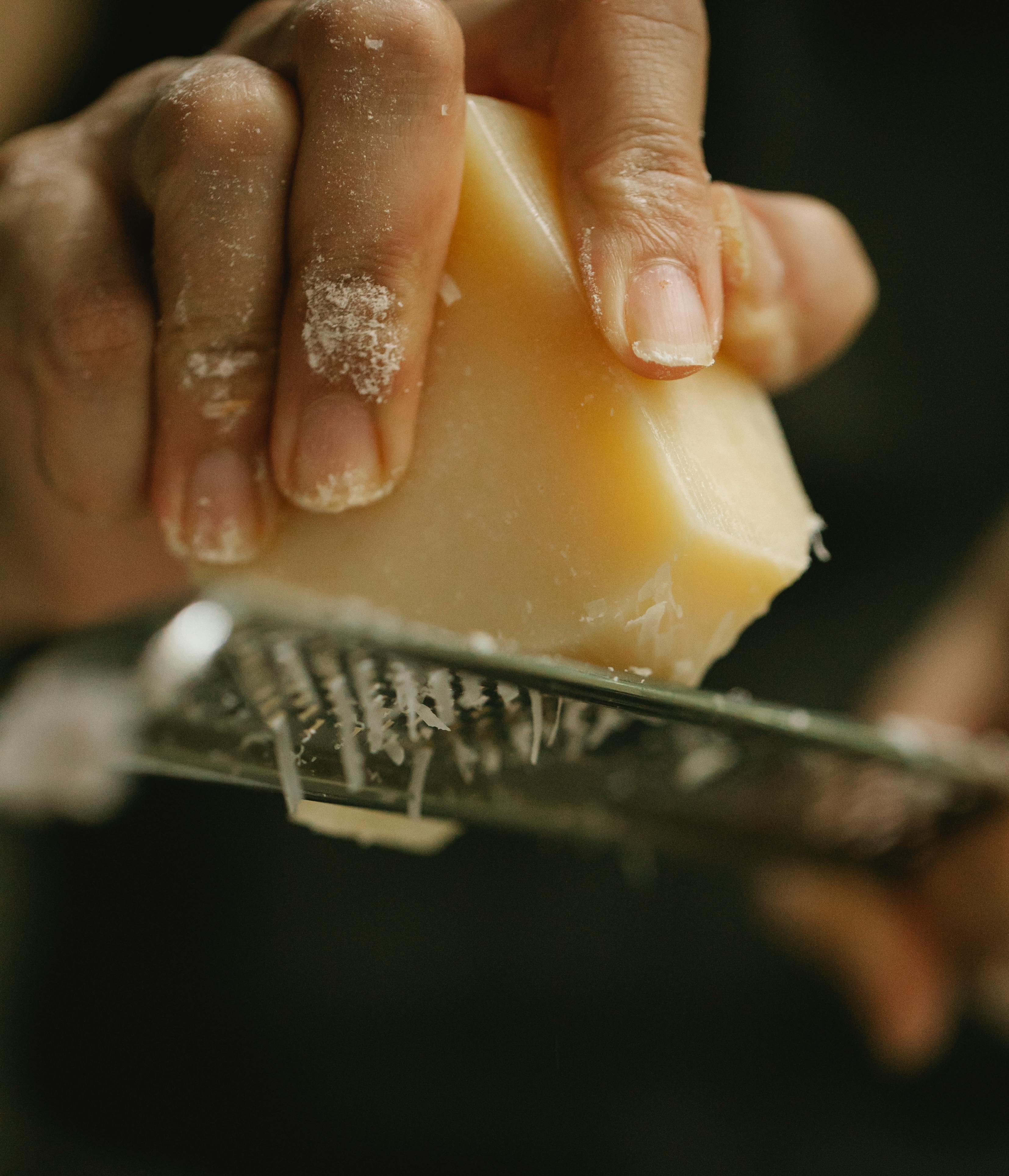 crop unrecognizable chef grating delicious cheese