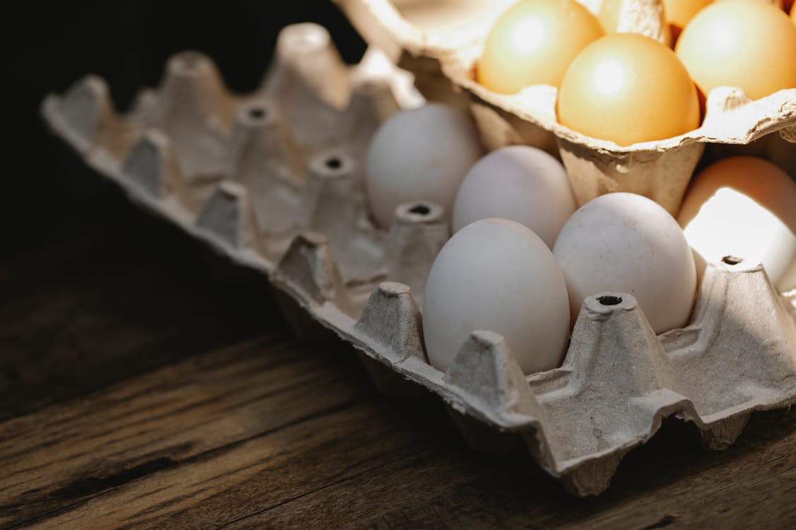 Free Carton box with fresh eggs placed on wooden surface Stock Photo
