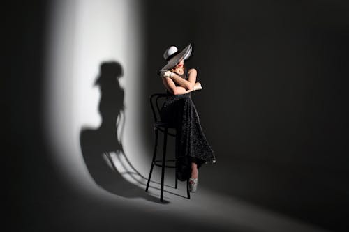 Женщина в черном платье сидит на стуле