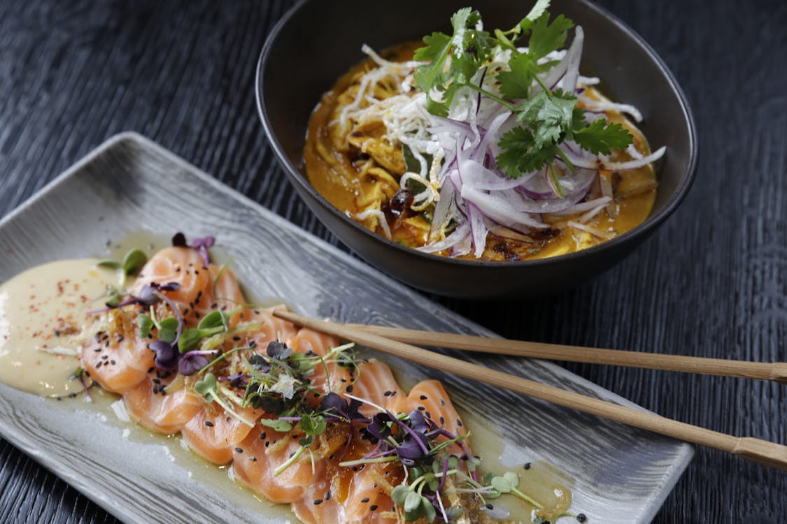 A sashimi and a bowl of another dish are served on the table.