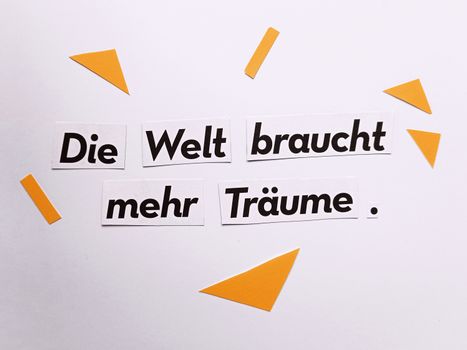 Cut-out text in German inspiring dreams, set on a clean white background with yellow accents.
