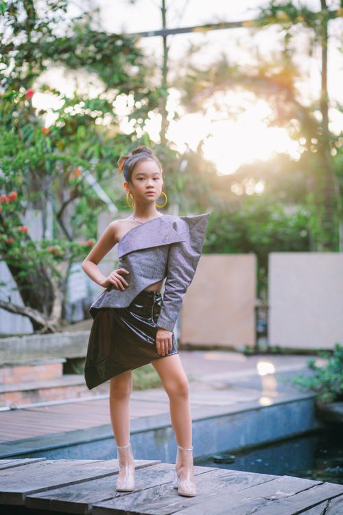 Free Young girl in fashionable attire posing in a sunlit greenhouse with greenery. Stock Photo