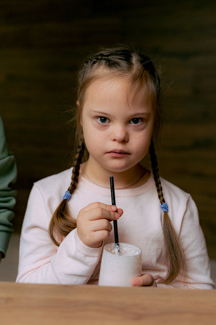 A Girl Holding The Straw Of Her Milkshake