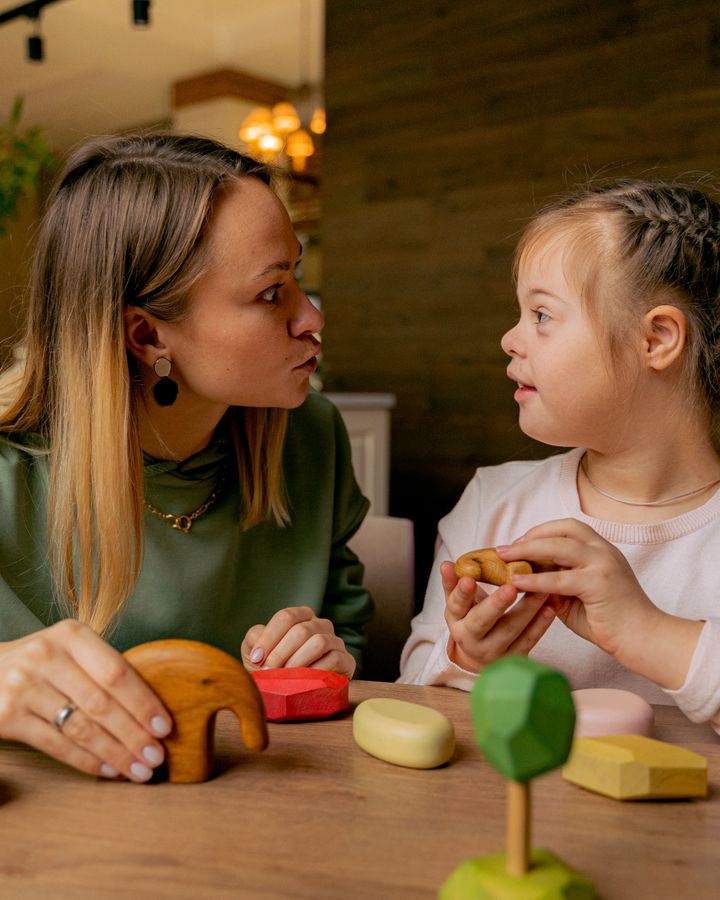 Woman supporting a child with Down syndrome during play and learning