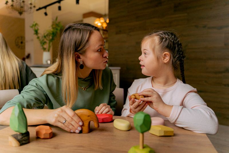 An adult and a child playing calmly together with wooden toys