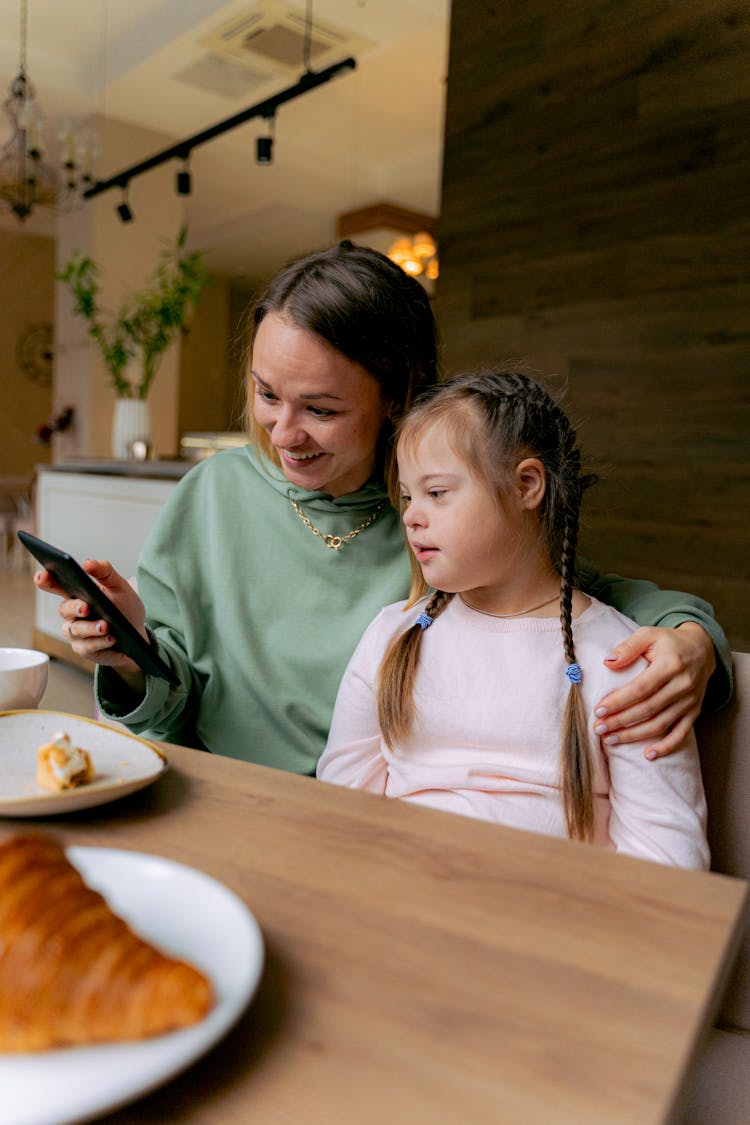 A Woman And Girl Looking A Smartphone