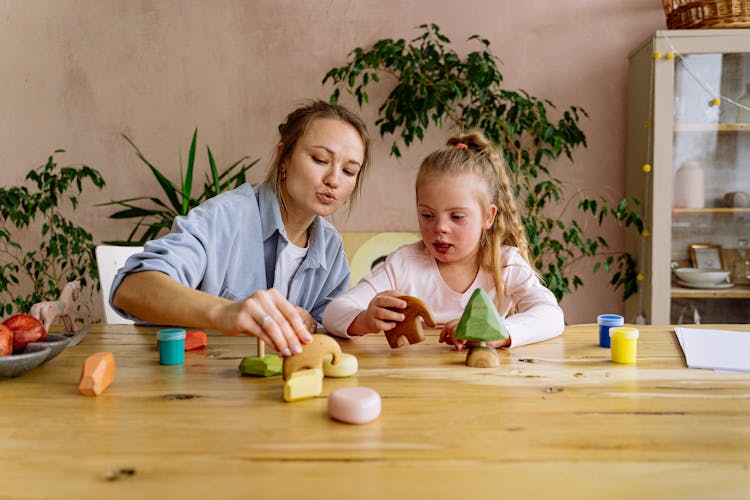 Mother And Daughter Playing With Toys On Wooden Table