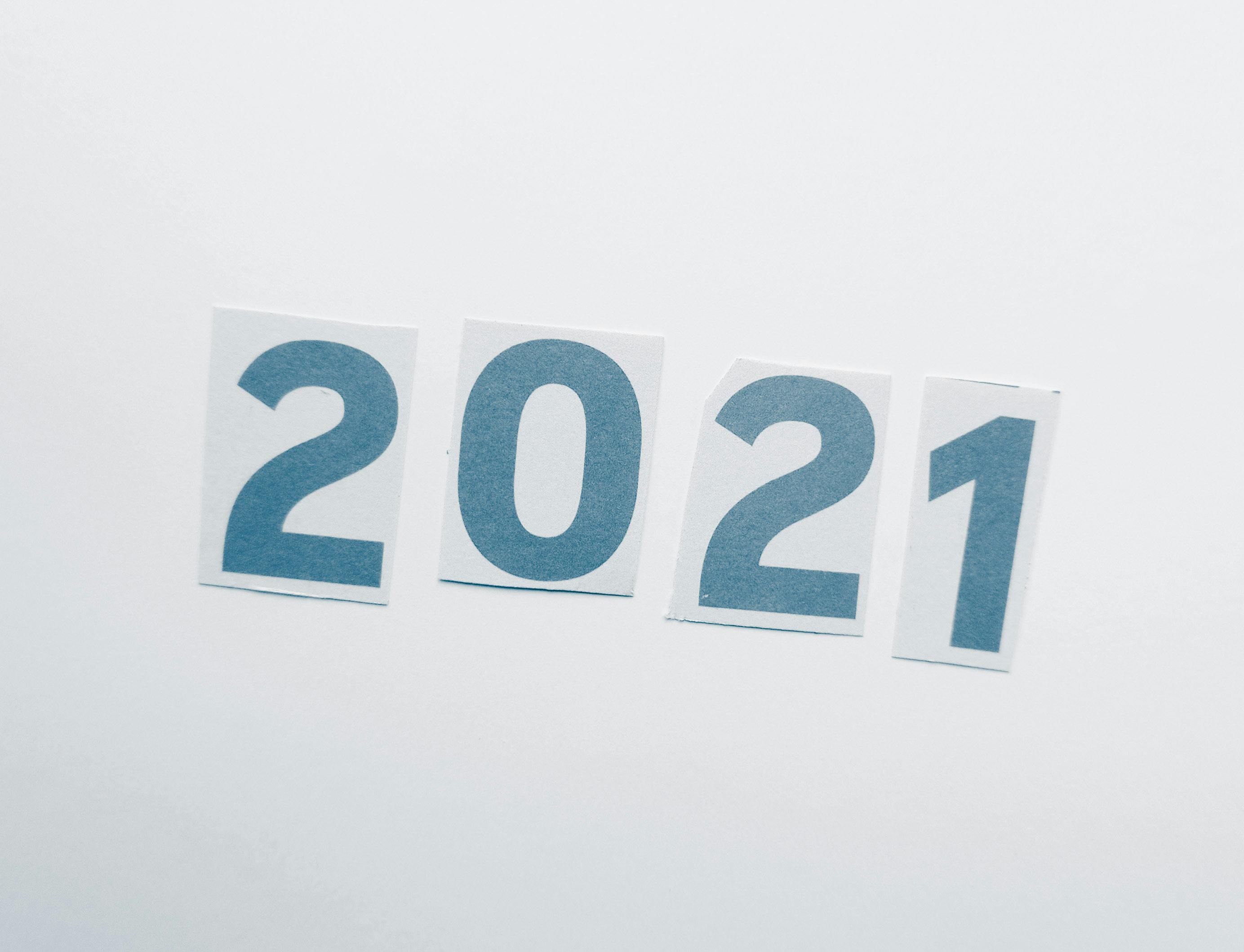 Simple paper cutout showing the year 2021 on a plain background.