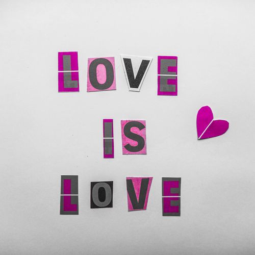 Free Minimalist typography design with 'Love is Love' message and paper heart on white background. Stock Photo