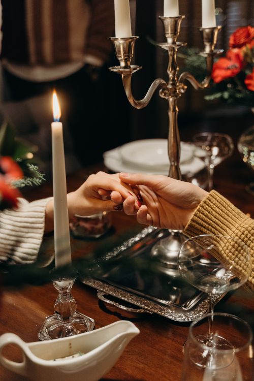 Free A romantic candlelit dinner setting with a couple holding hands across the table. Stock Photo
