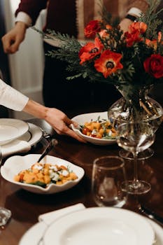 Beautiful table setup with a vibrant floral centerpiece and a delicious plate of salad being served.