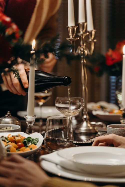 Free Close-up of champagne being poured into a coupe glass at an elegant dinner setting. Stock Photo