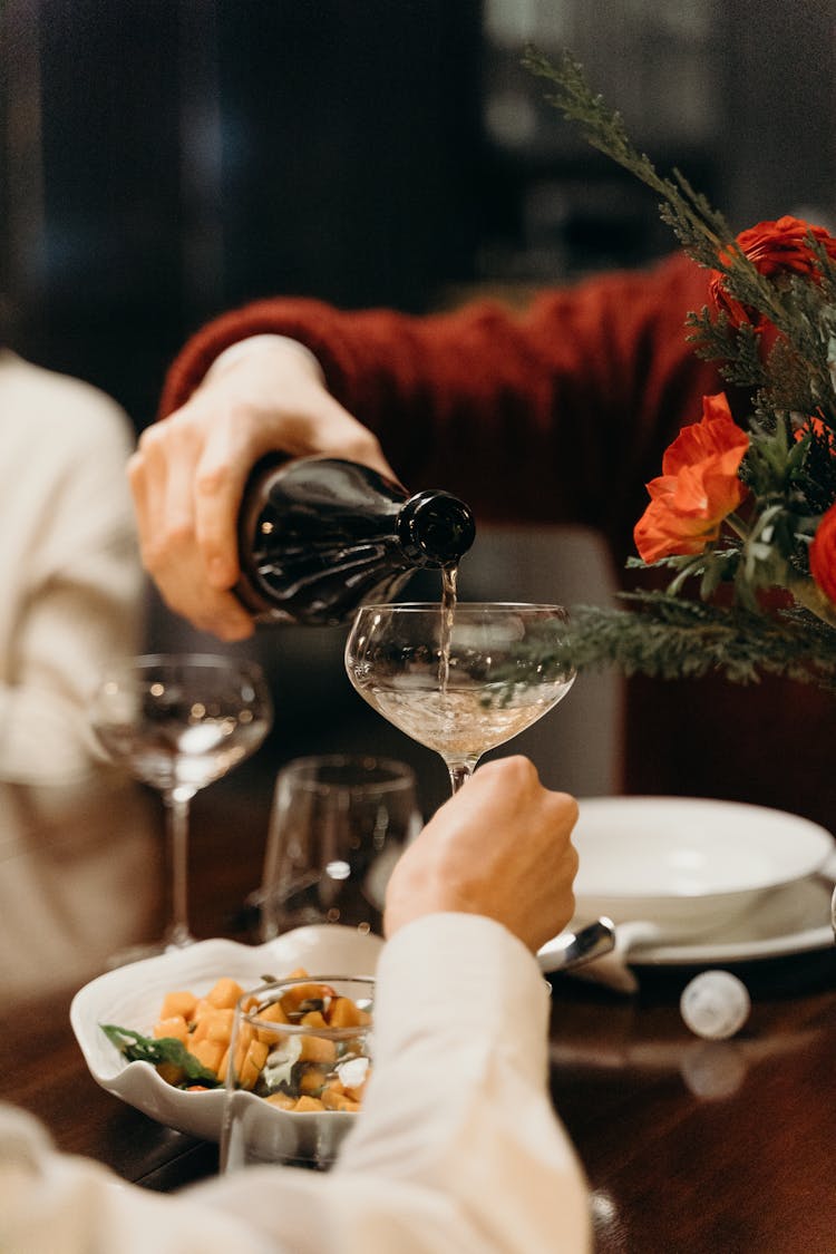 A Person Pouring A Champagne On A Glass