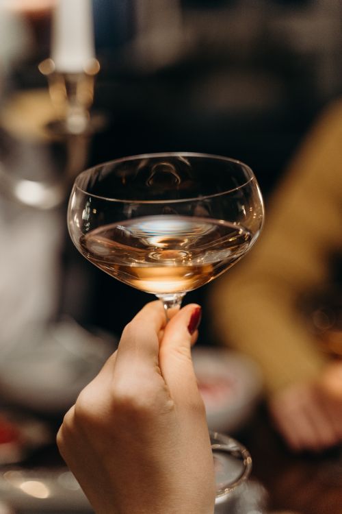 Free Close-up of a hand holding a coupe glass filled with champagne, perfect for celebratory occasions. Stock Photo