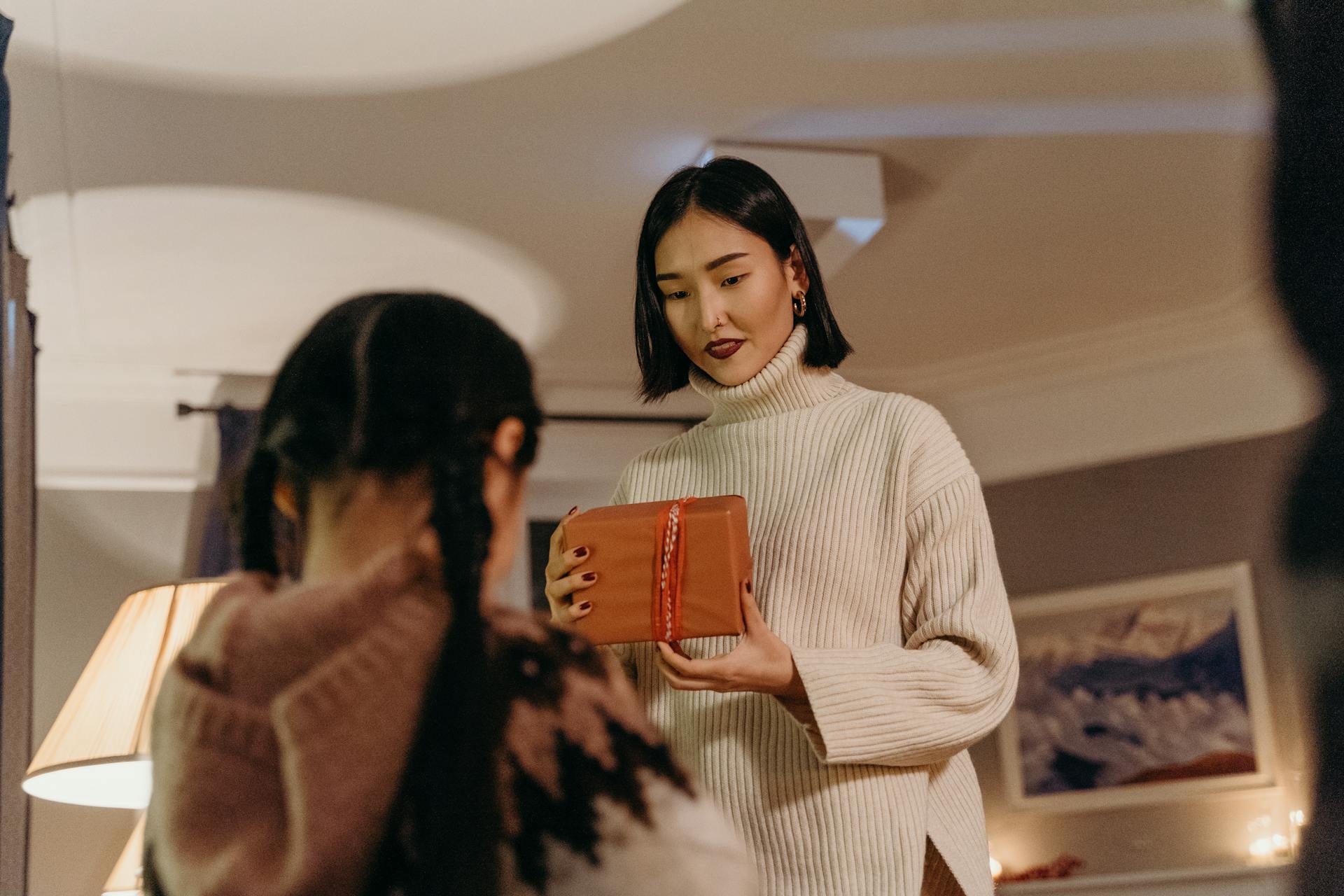 Mother and daughter share a special moment as they exchange a gift indoors.