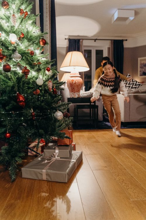 Free Child running happily towards Christmas gifts under a decorated tree indoors. Stock Photo