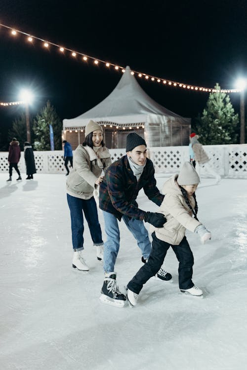 A Happy Family Wearing Winter Jacket while Skating Together