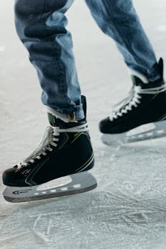 Person wearing jeans and ice skates on an ice rink, illustrating winter sports activity.