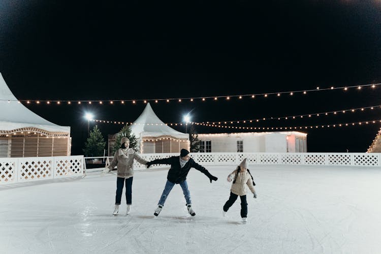 Family Enjoying Ice Skating At Nighttime