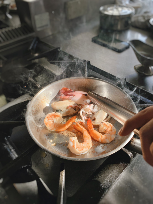Free Delicious seafood including shrimp and squid cooking in a frying pan on a stove. Stock Photo