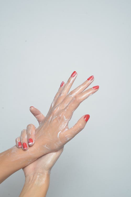 Person with Red Nail Polish and Cream on Hands