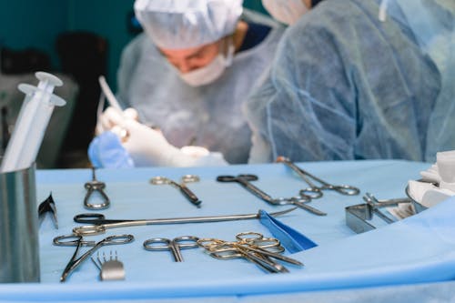 Free Medical Instruments and Surgeon Performing a Surgery  Stock Photo