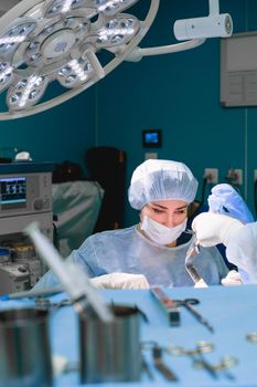A female surgeon focuses intently during a surgical procedure in a modern operating room.