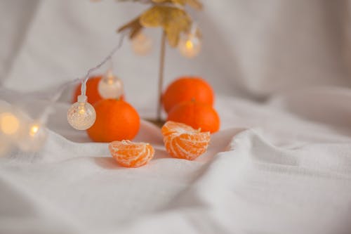 New Year composition of bright fresh mandarins and glowing garland with lanterns on white background