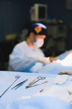 Focused surgeon in sterile operating room setting with surgical tools in foreground.