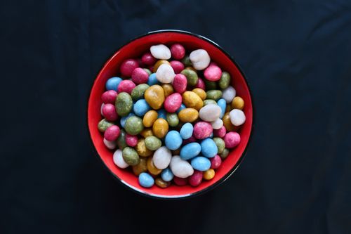 Free A vibrant assortment of candies in a striking red bowl against a dark background. Stock Photo