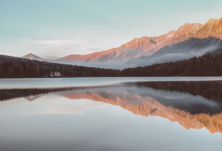 Serene mountain landscape with lake reflection at dawn, perfect for a peaceful wallpaper.