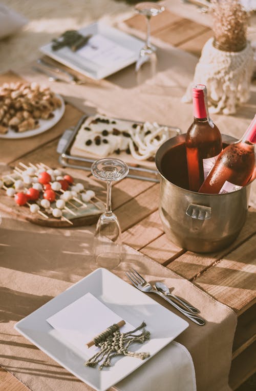 Champagne Bottles on Stainless Steel Bucket Beside Wine Glass on Wooden Table