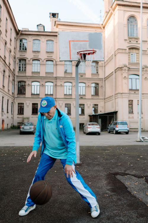 Free Elderly man in blue tracksuit plays basketball in a city courtyard. Stock Photo