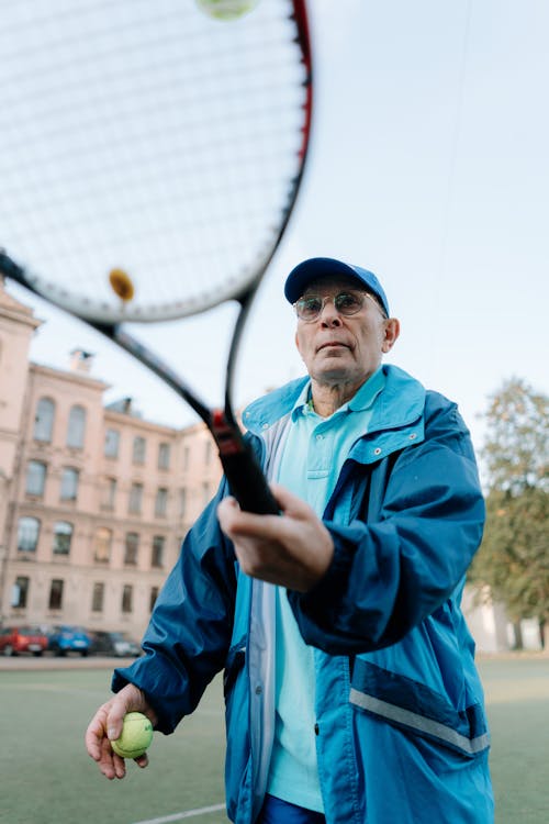Free Adult Man in Blue Jacket Holding a Tennis Racket and Ball Stock Photo