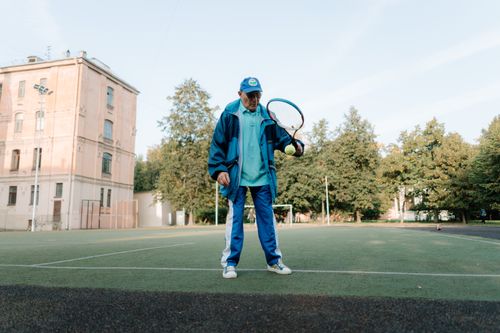 Free Elderly man enjoying tennis on an outdoor court, promoting active lifestyle. Stock Photo