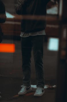 Reflection of a person in casual wear on an urban street window.