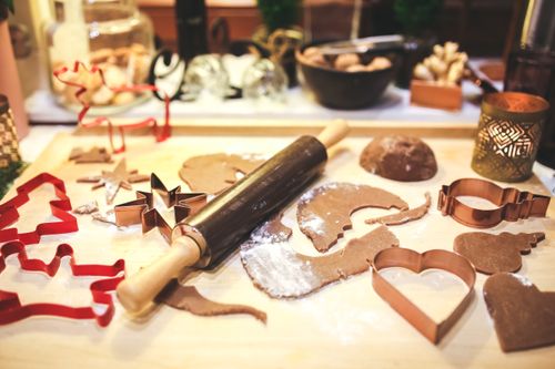 Free Festive gingerbread cookie shapes, dough, and rolling pin on a kitchen table during Christmas baking. Stock Photo