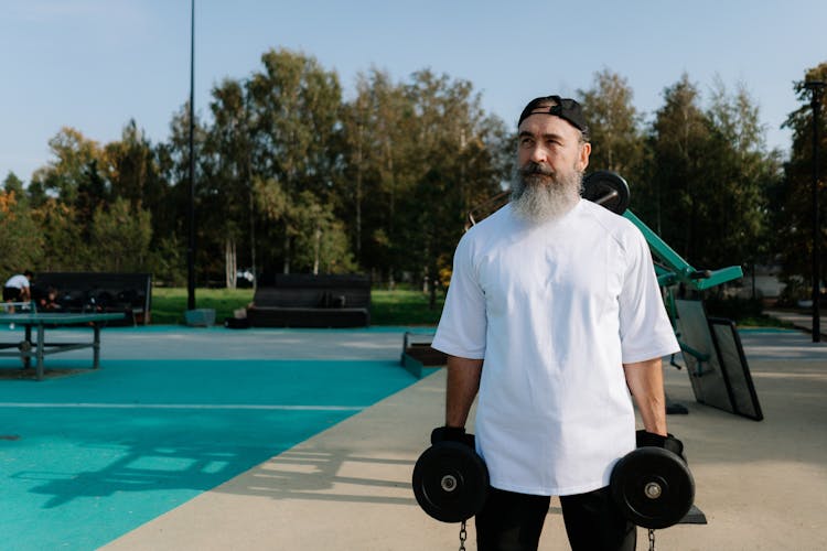 Bearded Man In White Shirt Holding Dumbbells