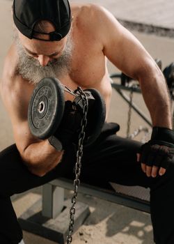 A senior man with a beard working out with dumbbells, showcasing strength and fitness.