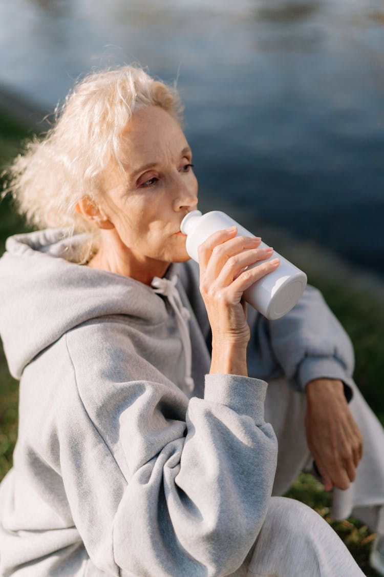 Woman In Gray Hoodie Drinking From White Bottle Tumbler